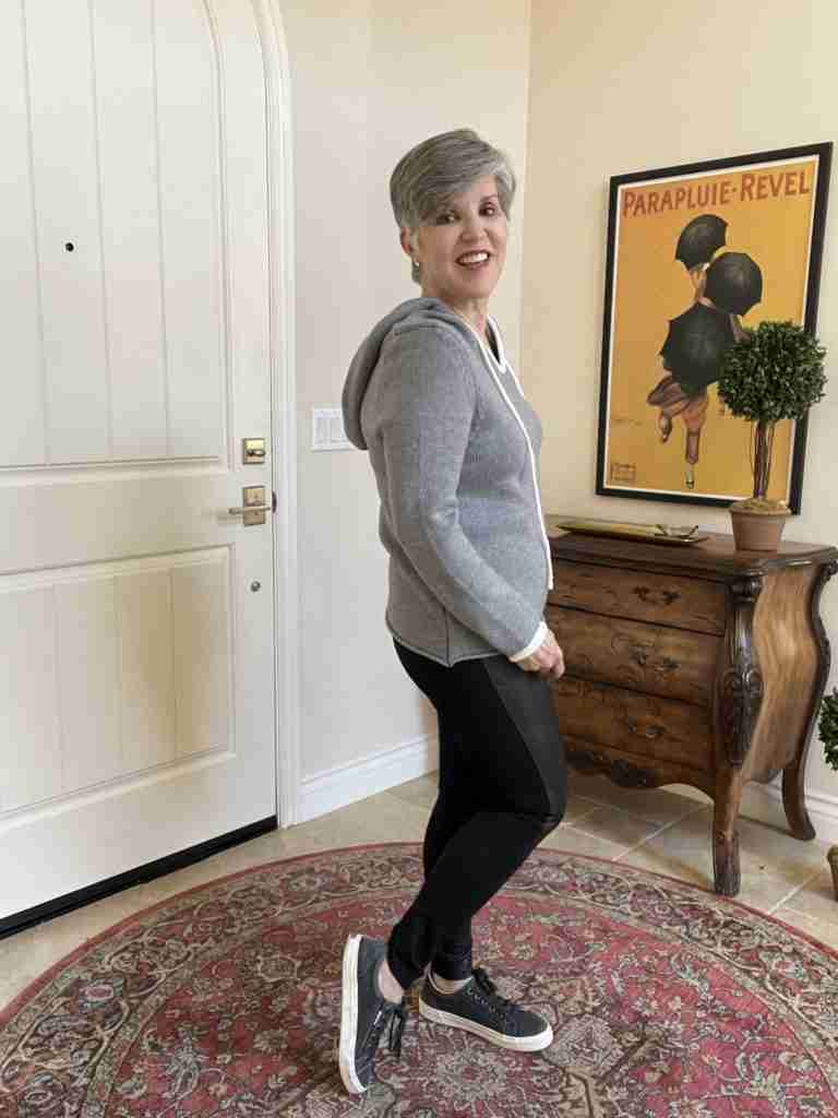 Black faux leather leggings worn with a gray hoodie and gray gym shoes for a casual look.