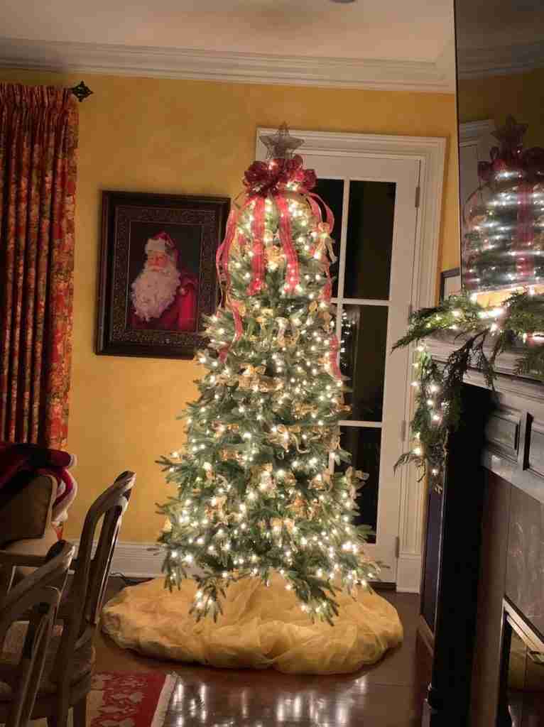 My gorgeous Christmas tree in my Chicago home as an introduction to lots more Christmas decorations in the home.
There is a tree with white lights, gold bows, gold skirt, and a Santa photo on the wall.