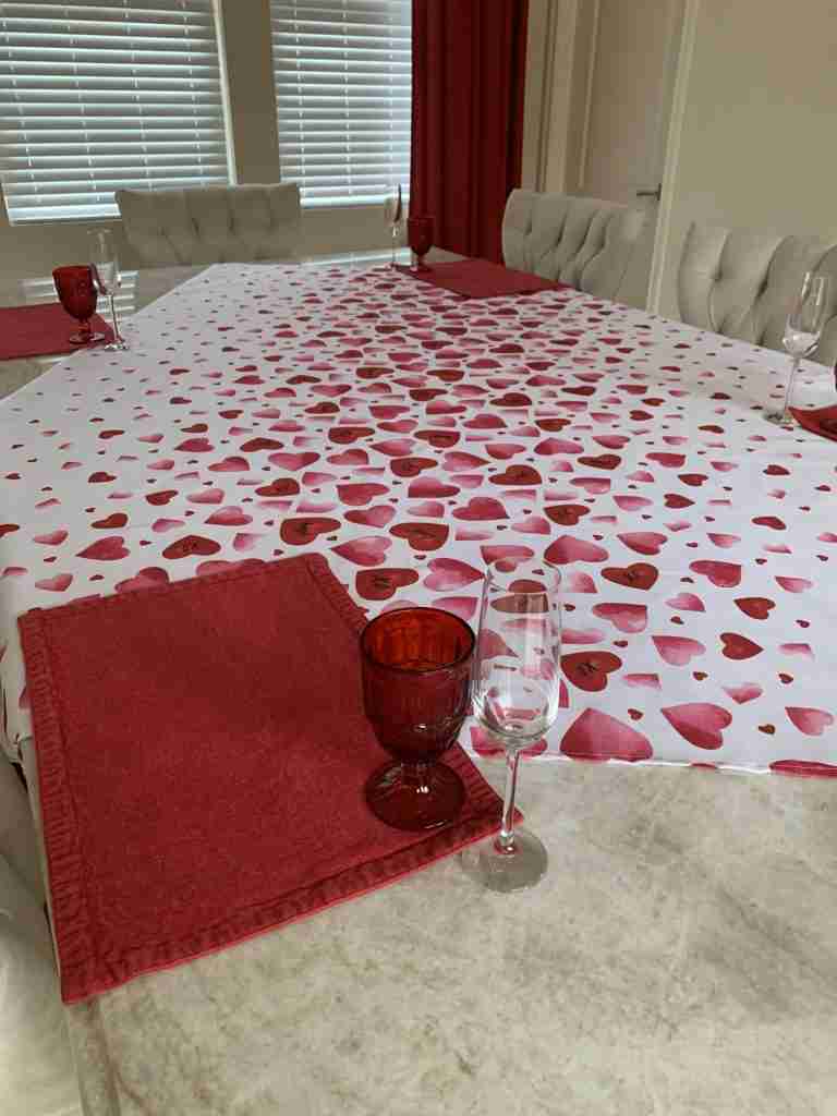valentines day tablescape with just the table cloth, red placemats, red goblets and champagne flutes in place.
