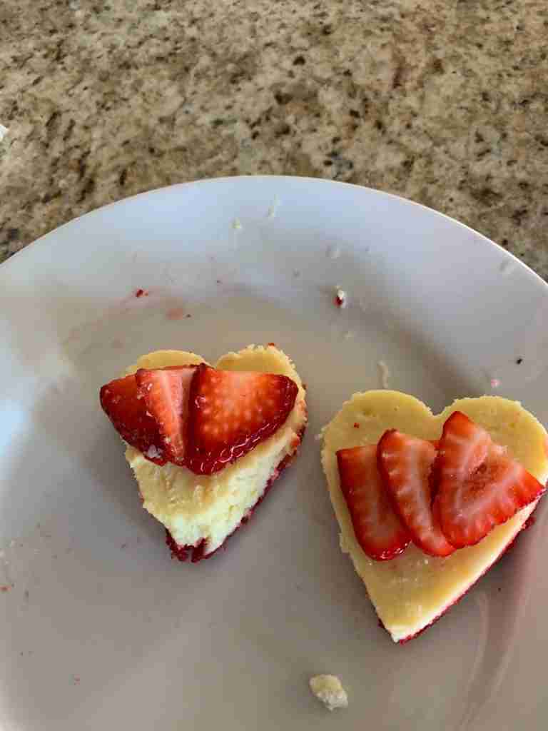 Success!  Heart-shaped cheesecakes on a platter garnished with strawberry slices.