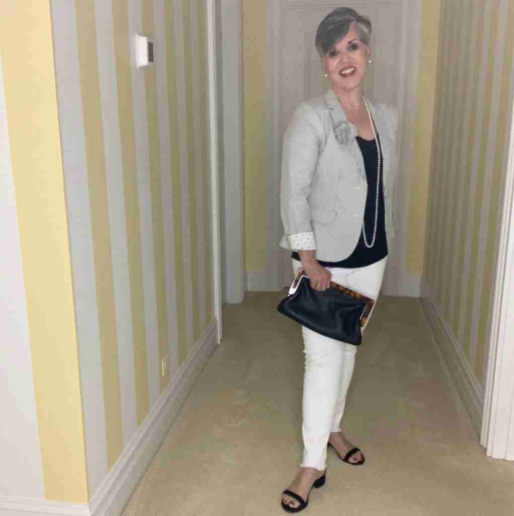 a black and white seersucker jacket over a black tank with white jeans, pearls and black suede sandals.