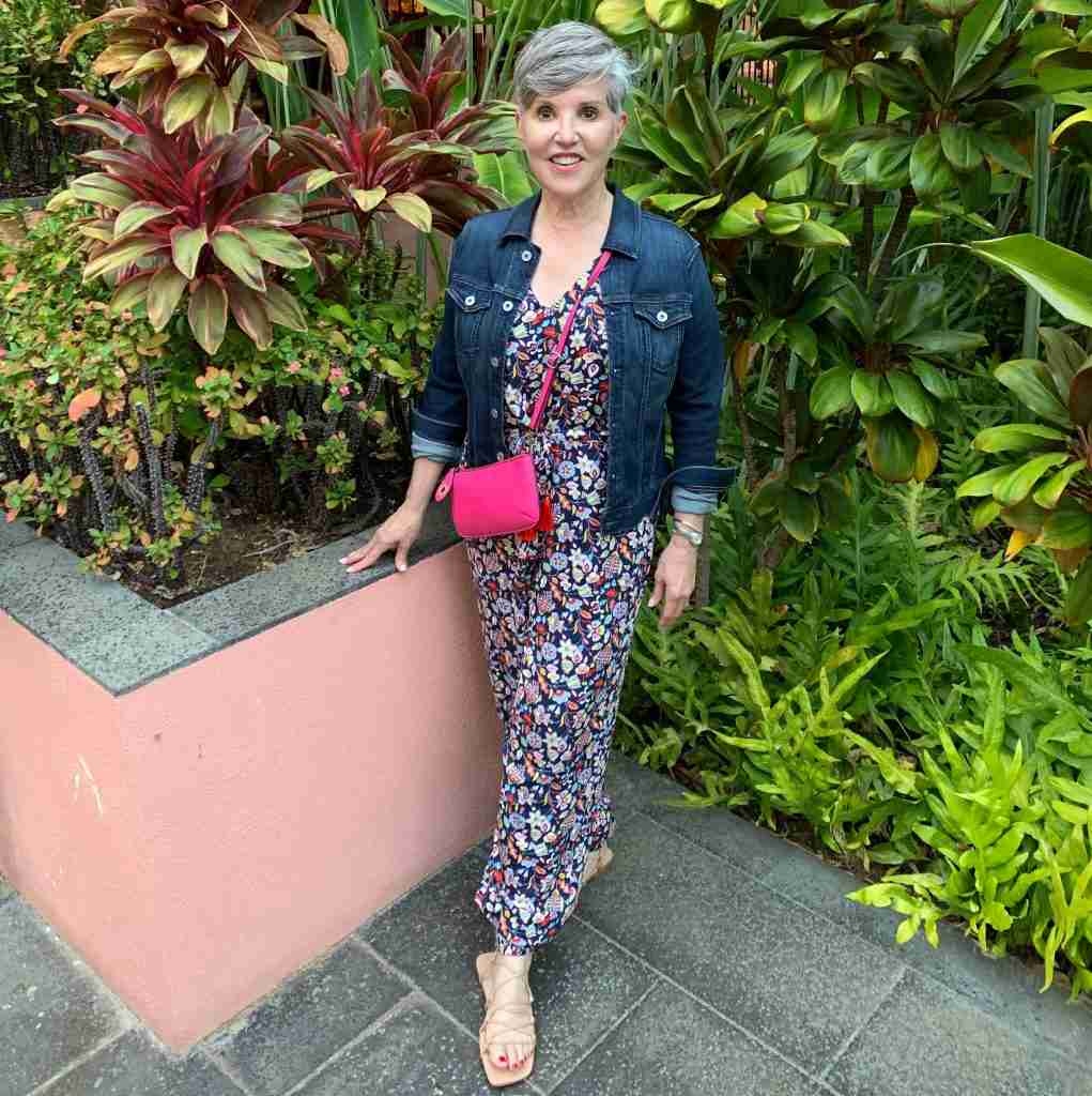 I am wearing a dark floral jumpsuit from Boden with a dark wash jean jacket and a hot pink cross body bag.