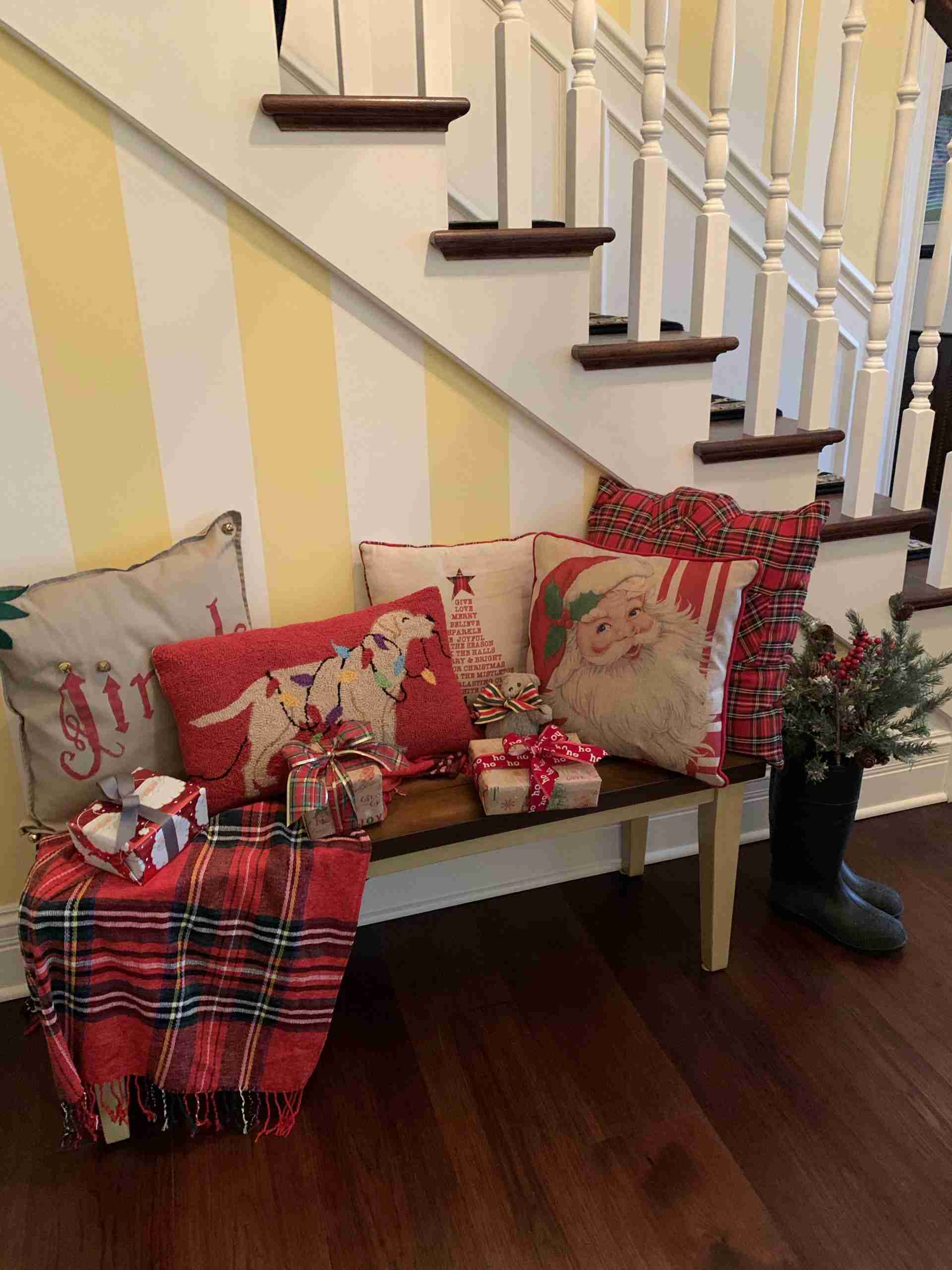My front hall bench decorated with a red plaid throw, wrapped presents, and Christmas pillows.  And garden boots filled with holiday greenery.