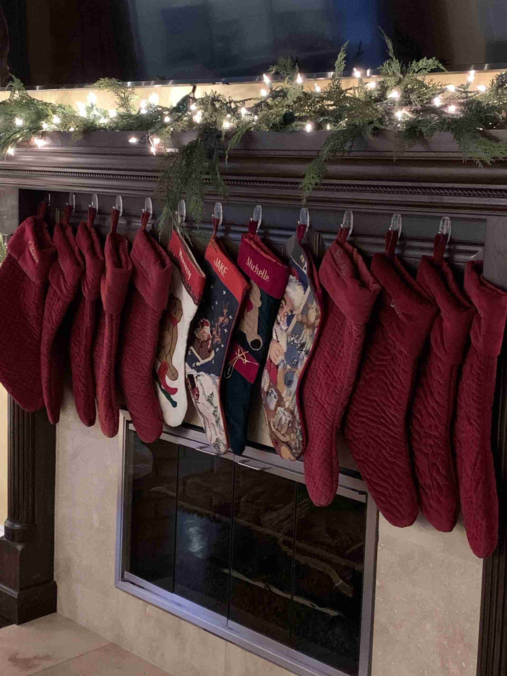 Christmas stockings hung by the fire under a white light lit mantel,