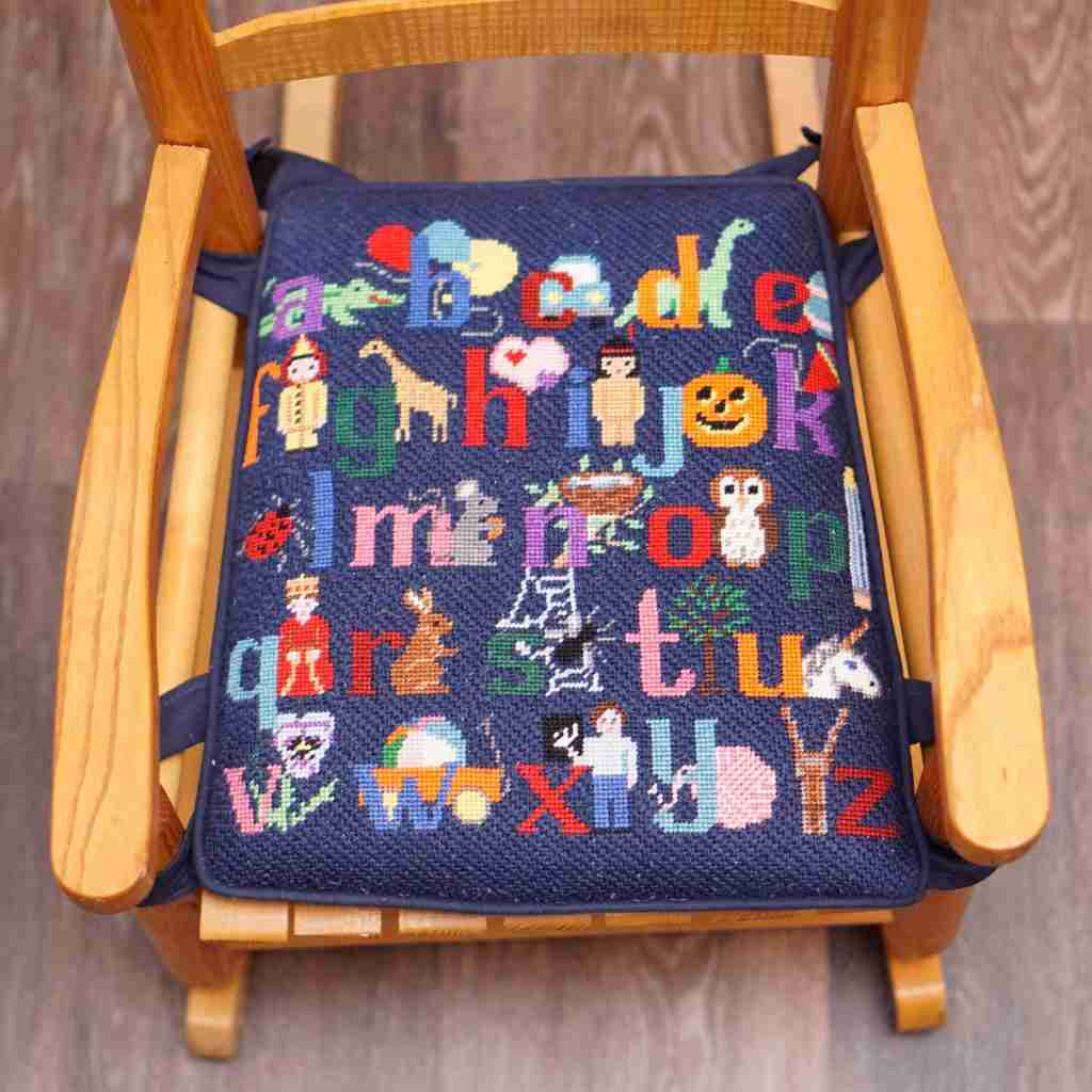 A frontal view of the natural rocker with the navy cushion and the ABC's design.