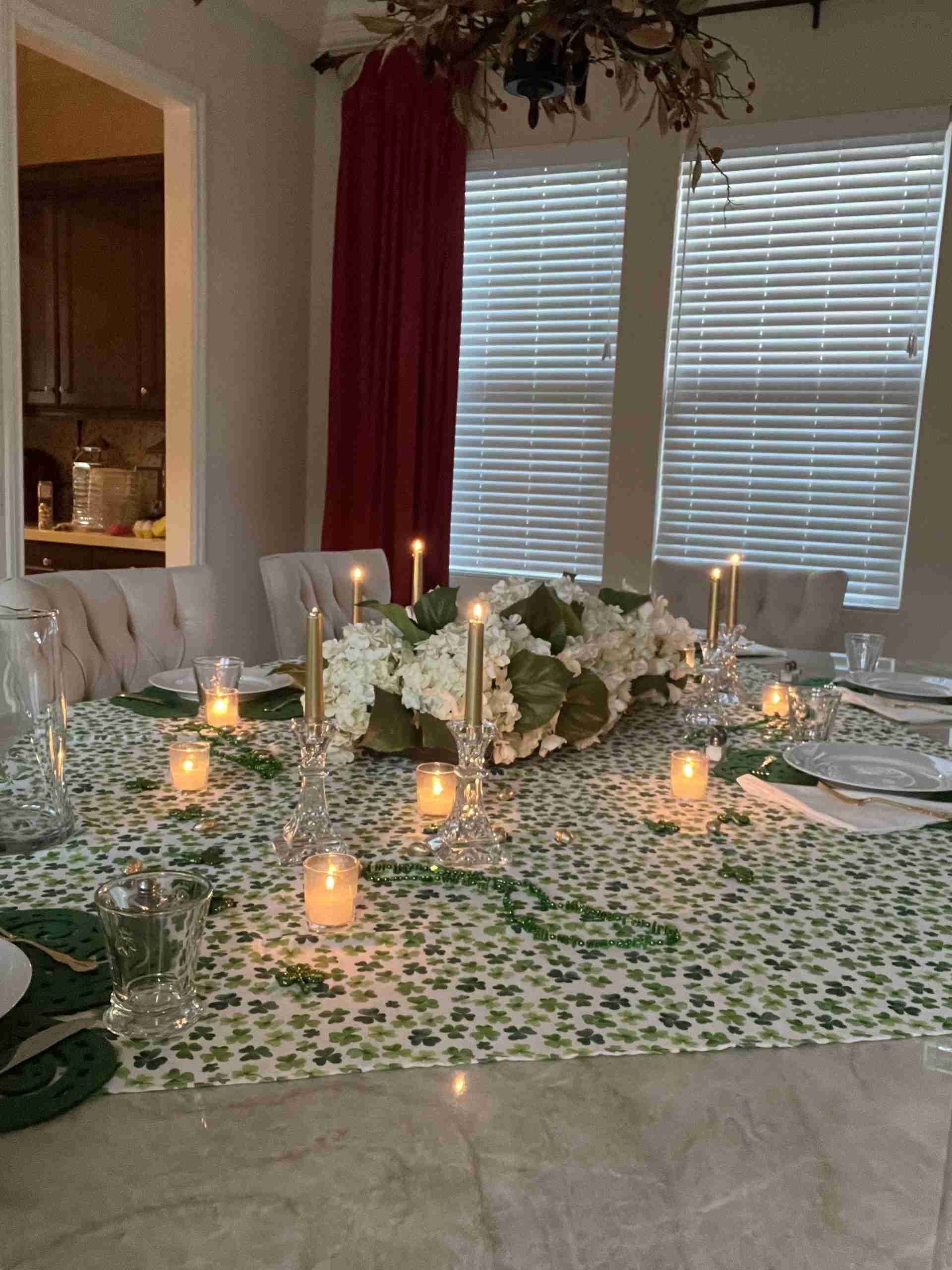 Here's and Fun St Patricks Day Tablescape! Green and white shamrock tablecloth with green shamrock placemats, white napkins and votive candles. I added crystal candlesticks with gold tapers, green Mardi Gras beads, and sparkly green shamrocks with gold foil-wrapped chocolate eggs.