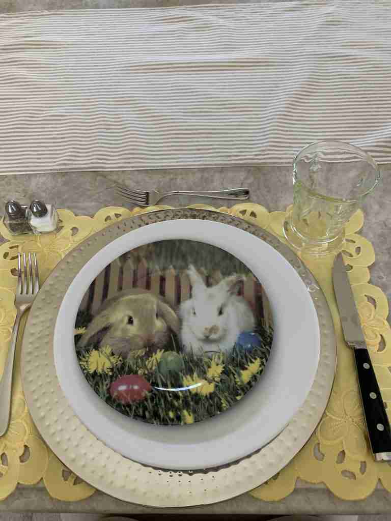 Darling little bunny salad plates on a white dinner plate, with a silver charger and yellow placemat.