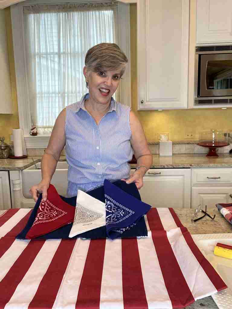 And here, this entertaining essential is a red and white striped tablecloth. which I have overlayed with woven royal blue placemats.  Lastly, I added red, white, and blue bandanas as napkins.