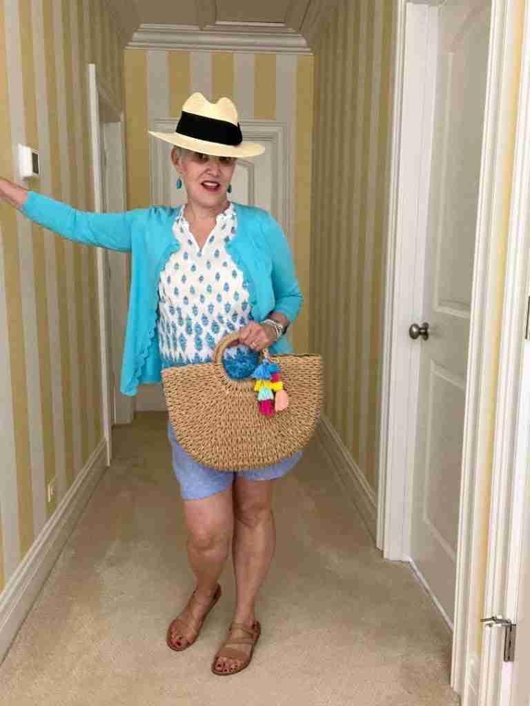I am in a white with blue Talbots cotton sleeveless top, a pretty blue scallop-edged cardigan, and blue linen shorts.  My Amazon straw bag has coordinating pompoms and my straw fedora hat was fun.