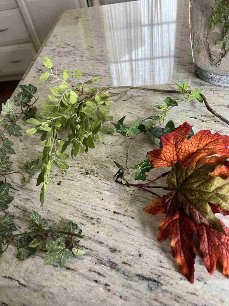 These are the "trailers" that I added at the end to finish off the arrangement.  Two sprigs of ivy, one spray of maple leaves, and a piece of greenery with little pale green leaves arranged in a cluster were the final touches to the "artificial sunflowers in a vase".