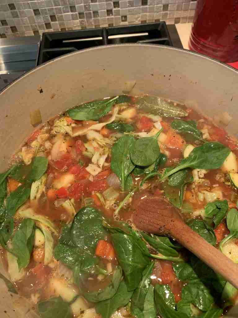 Here is the ten vegetable soup as it's simmering on the stove in a red soup pot.  The spinach leaves are on top and they look so vibrant!