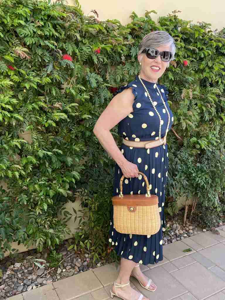 Here is the navy polka dot dress worn with pearls and a wicker handbag. I have on cream stappy sandals with a razor heel as well as a khaki canvas belt with honey-colored leather trim.  Here is a closeup of the wicker purse which has leather trim.