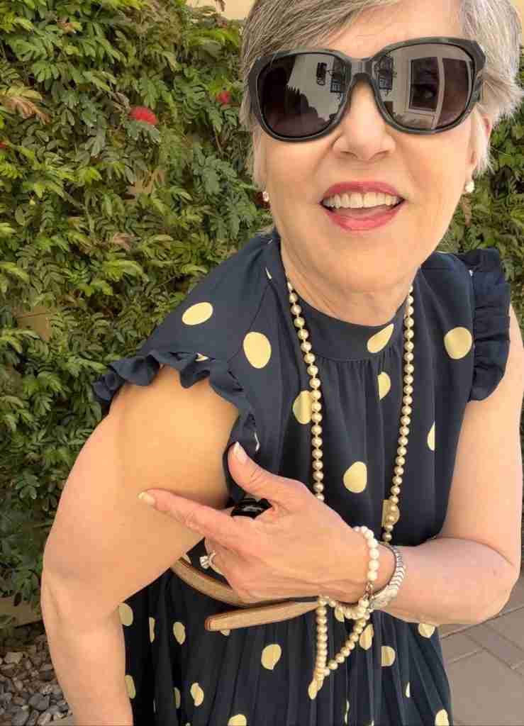 Here is the navy polka dot dress worn with pearls and a wicker handbag. I have on cream stappy sandals with a razor heel as well as a khaki canvas belt with honey-colored leather trim.  Here is a closeup of the small ruffle at the armhole,