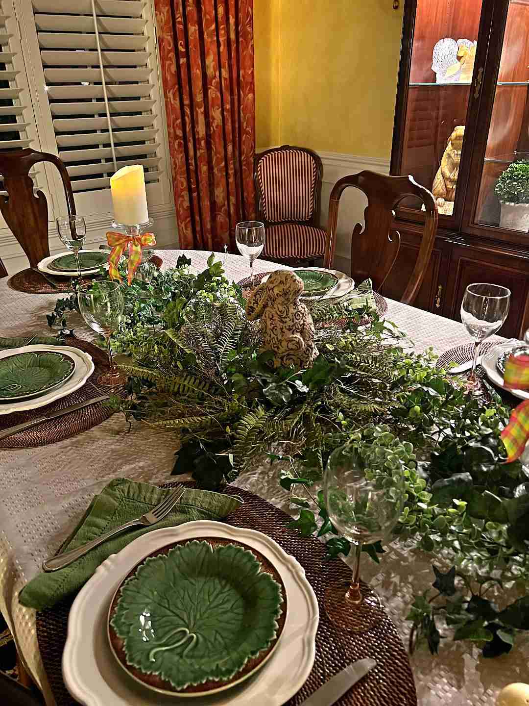 Here is a gorgeous Mothers Day table setting with olive green dessert plates. and napkins as well as lots of greenery making up the centerpiece.