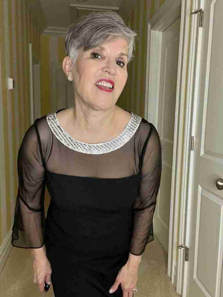 I am wearing a short black dress with a rhinestone neckline.  There is also illusion netting and pretty bell-shaped sleeves.