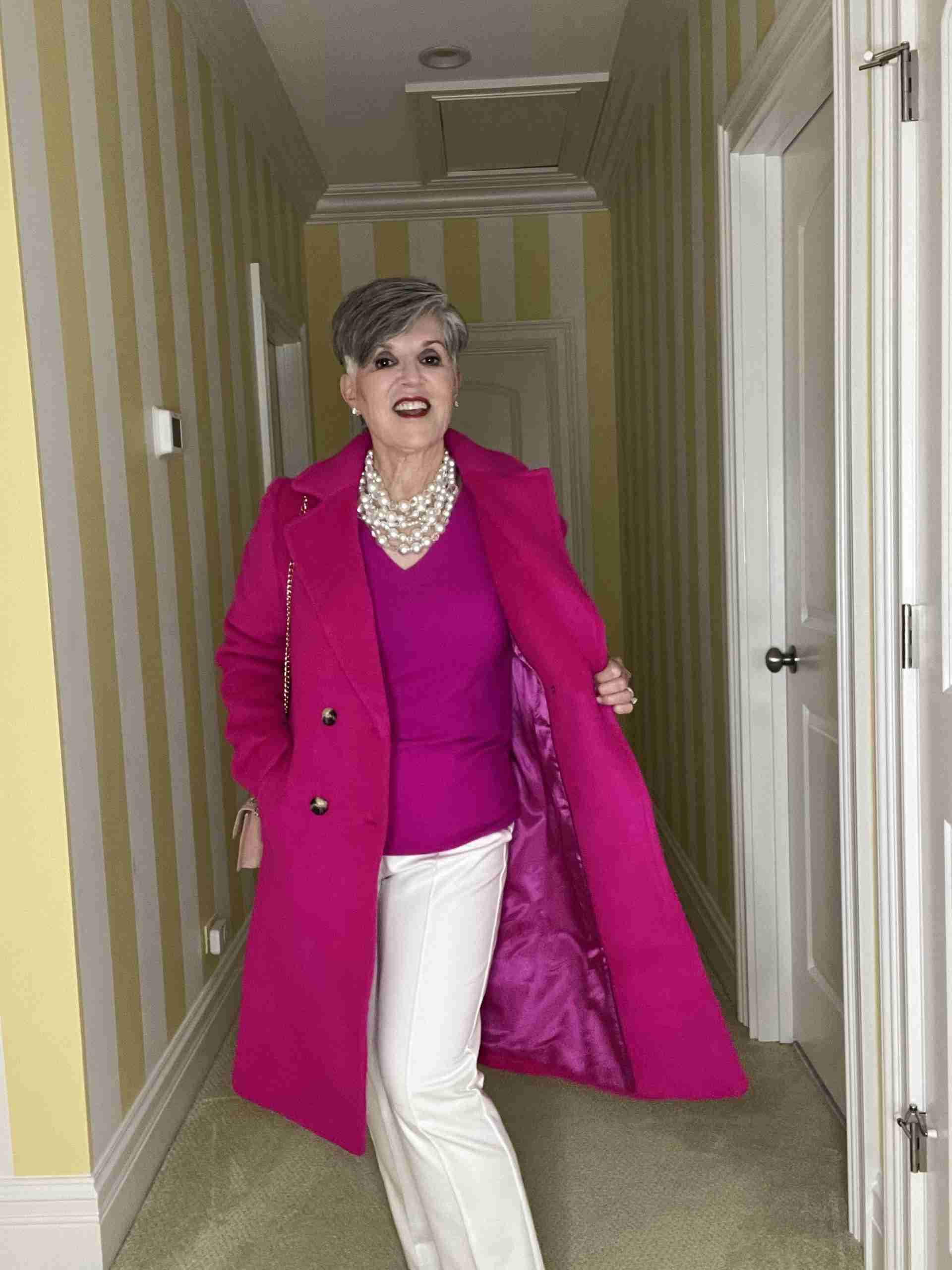 A fuchsia classic coat styled four ways. Here with white dress pants and a fuchsia v-neck sweater. Lastly, i am wearing a multi-stranded pearl choker.